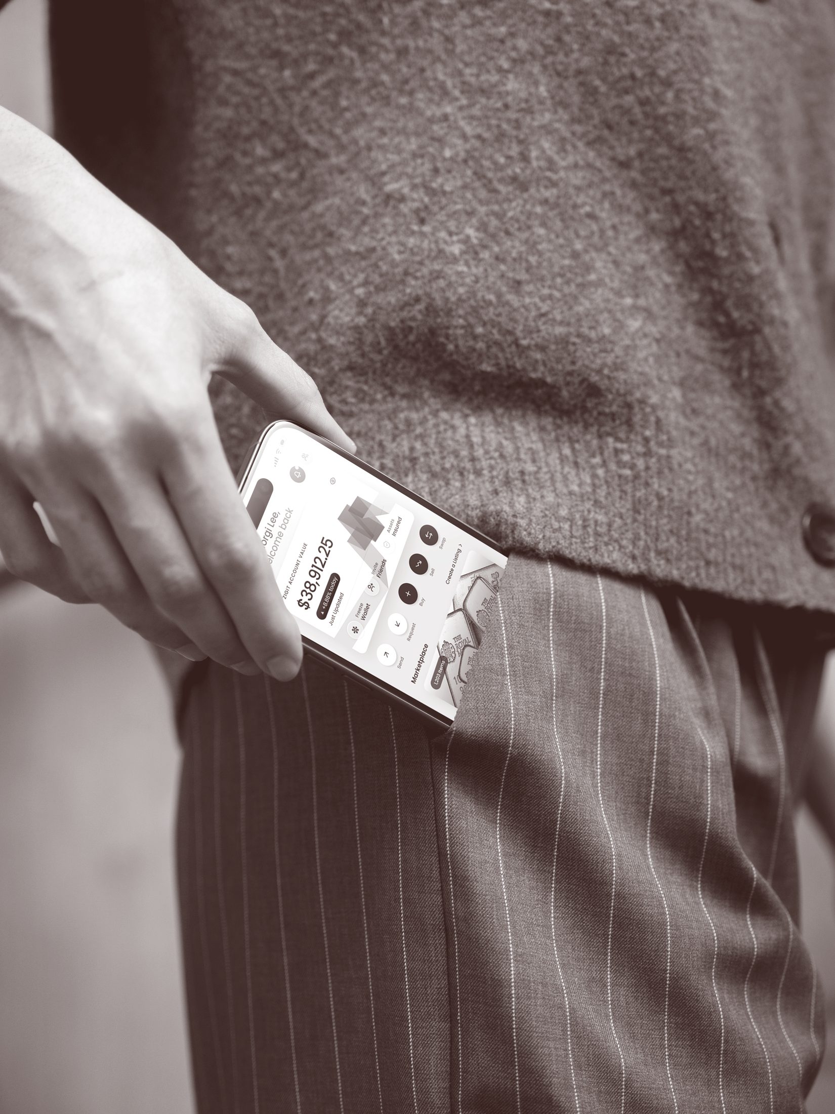 Black-and-white close-up of a hand lifting an iPhone showing the Zigit app out of a pinstriped trouser pocket